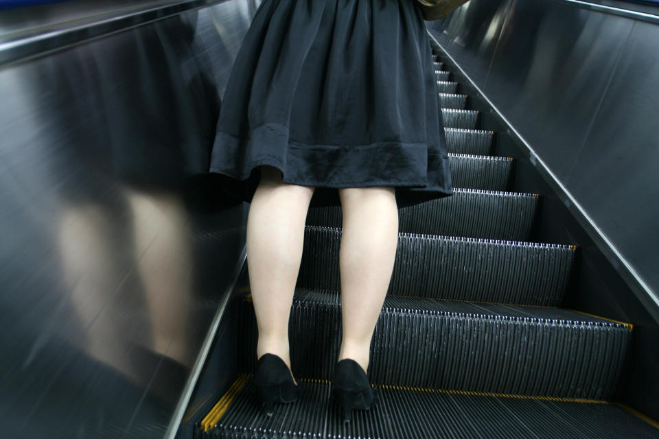 Woman's legs on the moving staircase