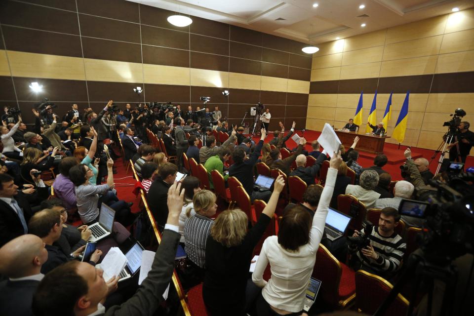 Ukraine's fugitive President Viktor Yanukovych, back left, gives a news conference as journalists raise arms to ask questions, in Rostov-on-Don, a city in southern Russia about 1,000 kilometers (600 miles) from Moscow, Friday, Feb. 28, 2014. Yanukovych has pledged to fight on for the country’s future. (AP Photo/Pavel Golovkin)