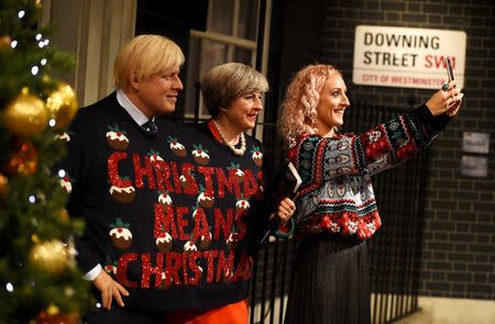 FILE PHOTO - FA woman poses next to Madame Tussauds' wax figures of Britain's Prime Minister Theresa May and Foreign Secretary Boris Johnson wearing one Christmas themed jumper between them and holding a sign, in London, December 13, 2017. REUTERS/Clodagh Kilcoyne