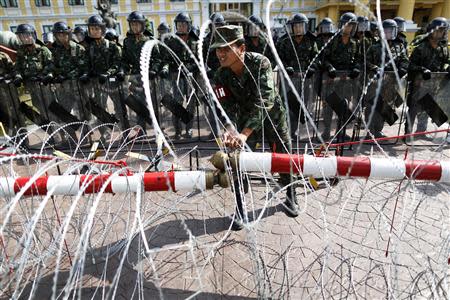 A security personnel adjusts razor wire as anti-government protesters arrive to the Defense Ministry in central Bangkok November 28, 2013. REUTERS/Damir Sagolj