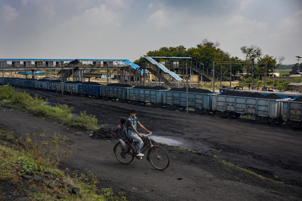 A boy cycles past a stationary freight train carrying coal at Chainpur village near Hazaribagh, in eastern state of Jharkhand, Sunday, Sept. 26, 2021. No country will see energy needs grow faster in coming decades than India, and even under the most optimistic projections part of that demand will have to be met with dirty coal power — a key source of heat-trapping carbon emissions. (AP Photo/Altaf Qadri)