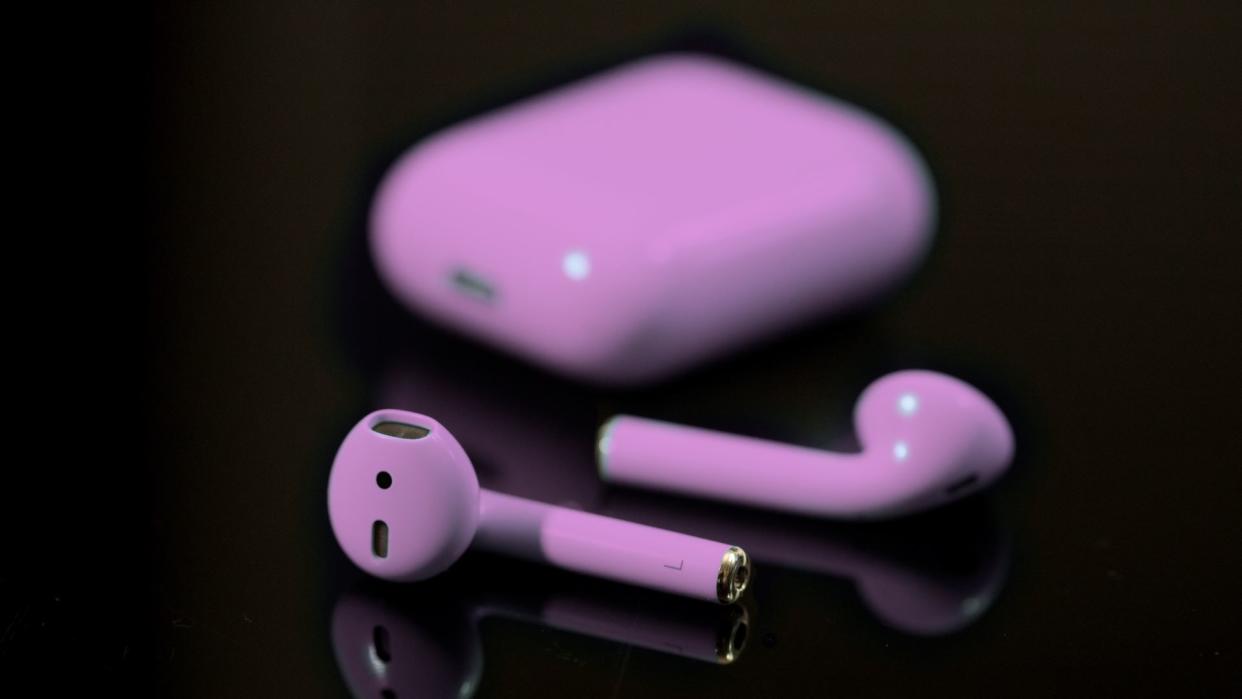  Airpods tinted purple on black background 