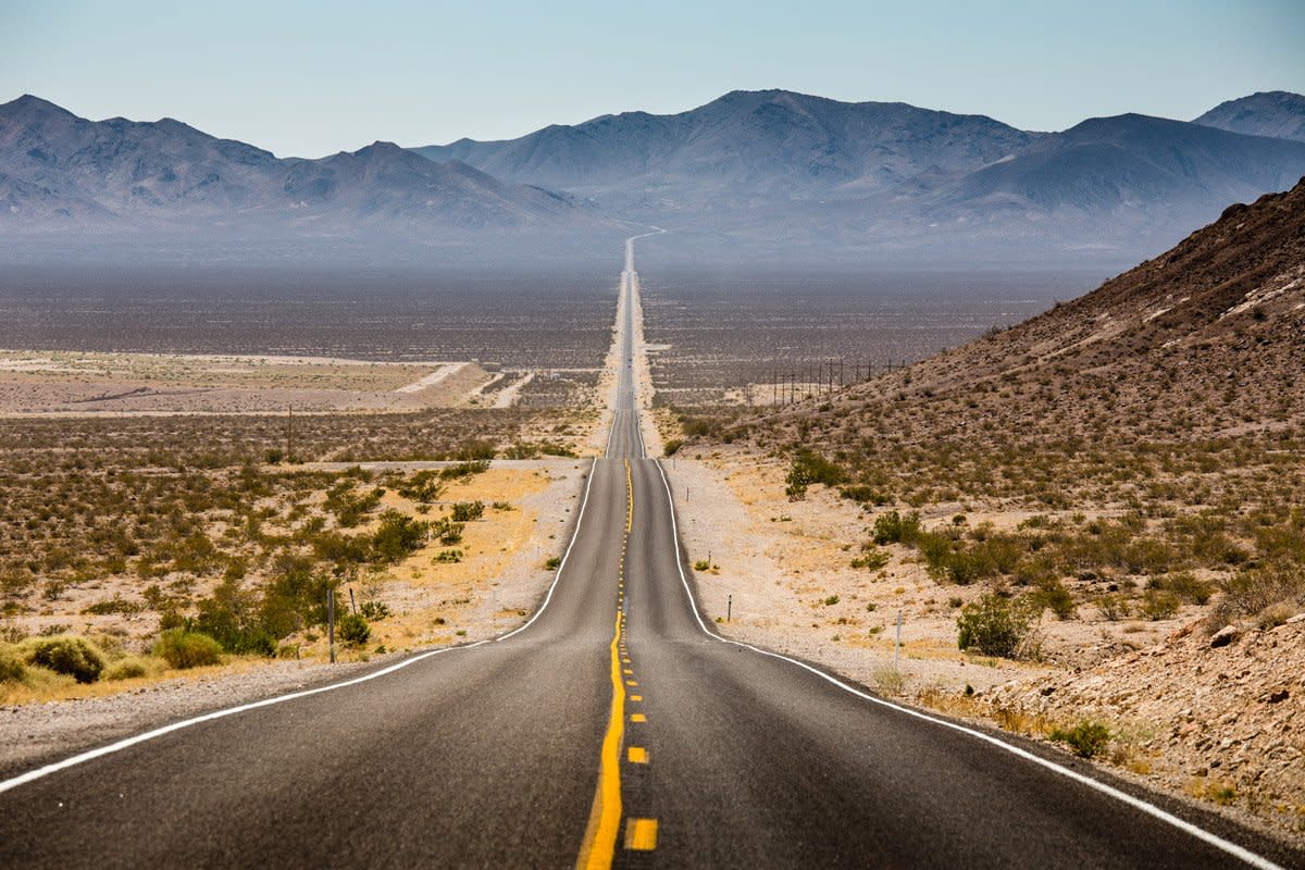 A road is shown with a view of deserts and canyons. 