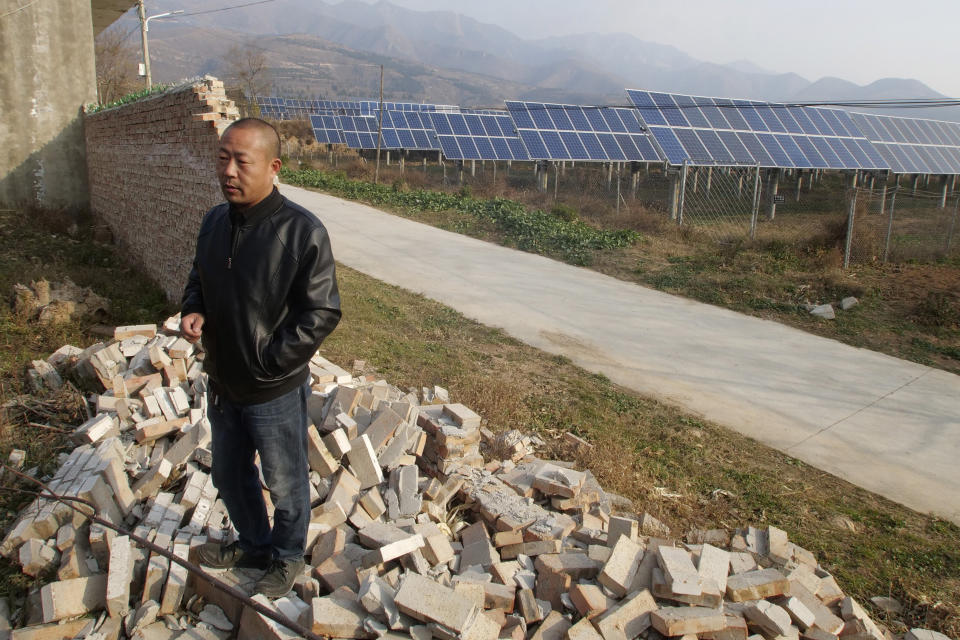 In this Nov. 28, 2019, photo, Chan Shicun, a construction materials trader, points to a wall he said local authorities destroyed after a disagreement with a massive government-backed solar project in Ruicheng County in central China's Shanxi Province. As world leaders gather in Madrid to discuss how to slow the warming of the planet, a spotlight is falling on China, the top emitter of greenhouse gases. China burns about half the coal used globally each year. Yet it's also the leading market for solar panels, wind turbines and electric vehicles. (AP Photo/Sam McNeil)