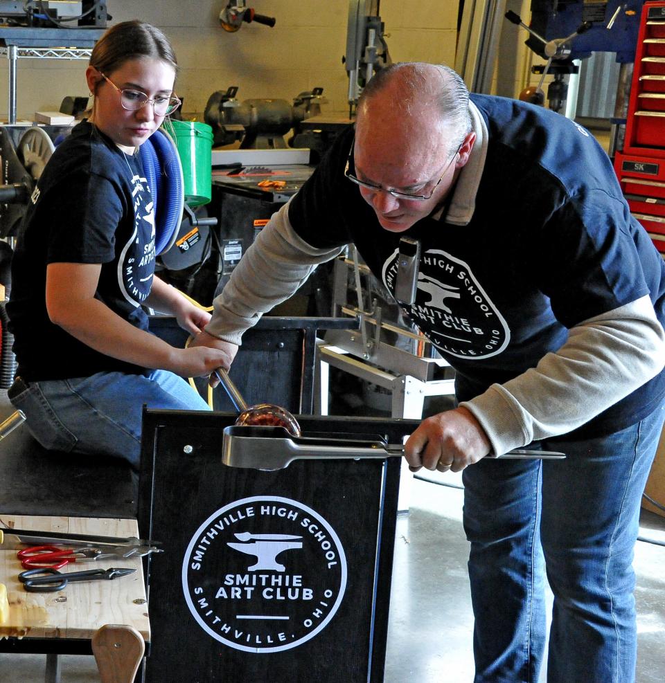 Smithville senior Vea Aney holds her hot glass stem while glass blower David Graeber forms the bottom.