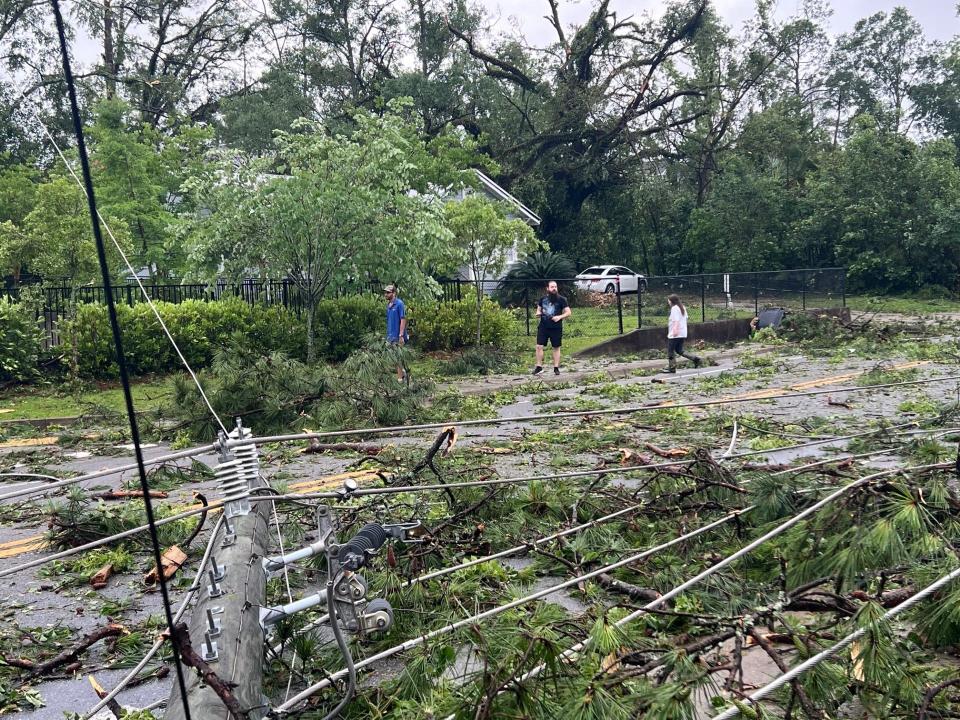 Francisco De La Fontaine, Q, and Sara Sweetapple navigate downed power lines along Lipona Drive, Friday May 10, 2024