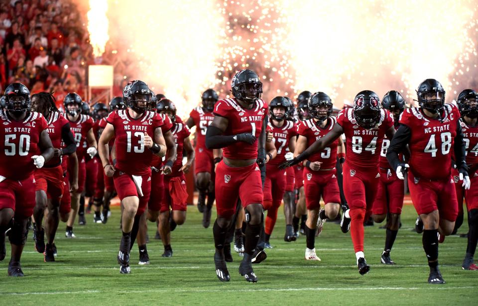 Sep 24, 2022; Raleigh, North Carolina, USA;  North Carolina State Wolfpack linebacker Isaiah Moore (1) and quarterback Devin Leary (13) lead their team onto the field prior to a game against the Connecticut Huskies at Carter-Finley Stadium.