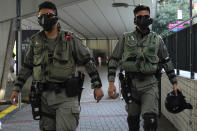 Riot police wearing masks patrol outside of a polling place in Hong Kong, Sunday, Nov. 24, 2019. Long lines formed outside Hong Kong polling stations Sunday in elections that have become a barometer of public support for anti-government protests now in their sixth month. (AP Photo/Vincent Yu)