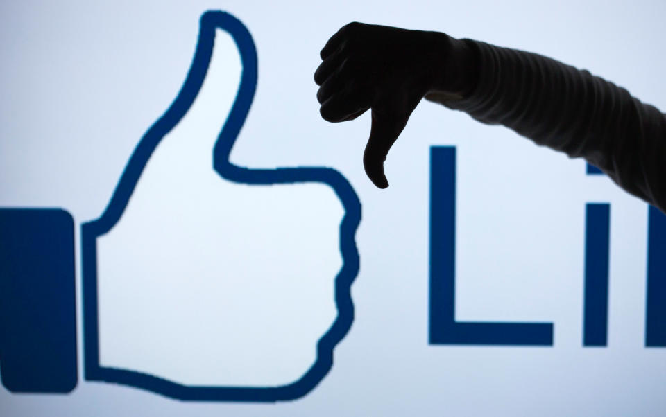 ILLUSTRATION - A woman makes the 'thumbs down' sign with her fist and thumb in front of an enlarged 'Like' symbol of the social netweorking site Facebook in Schwerin, Germany, 04 April 2013 (STAGED PICTURE). The social network counts more than 25 million users in Germany alone, but it keeps losing more and more especially young users to other online services. Photo: Jens Buettner | usage worldwide   (Photo by Jens Büttner/picture alliance via Getty Images)