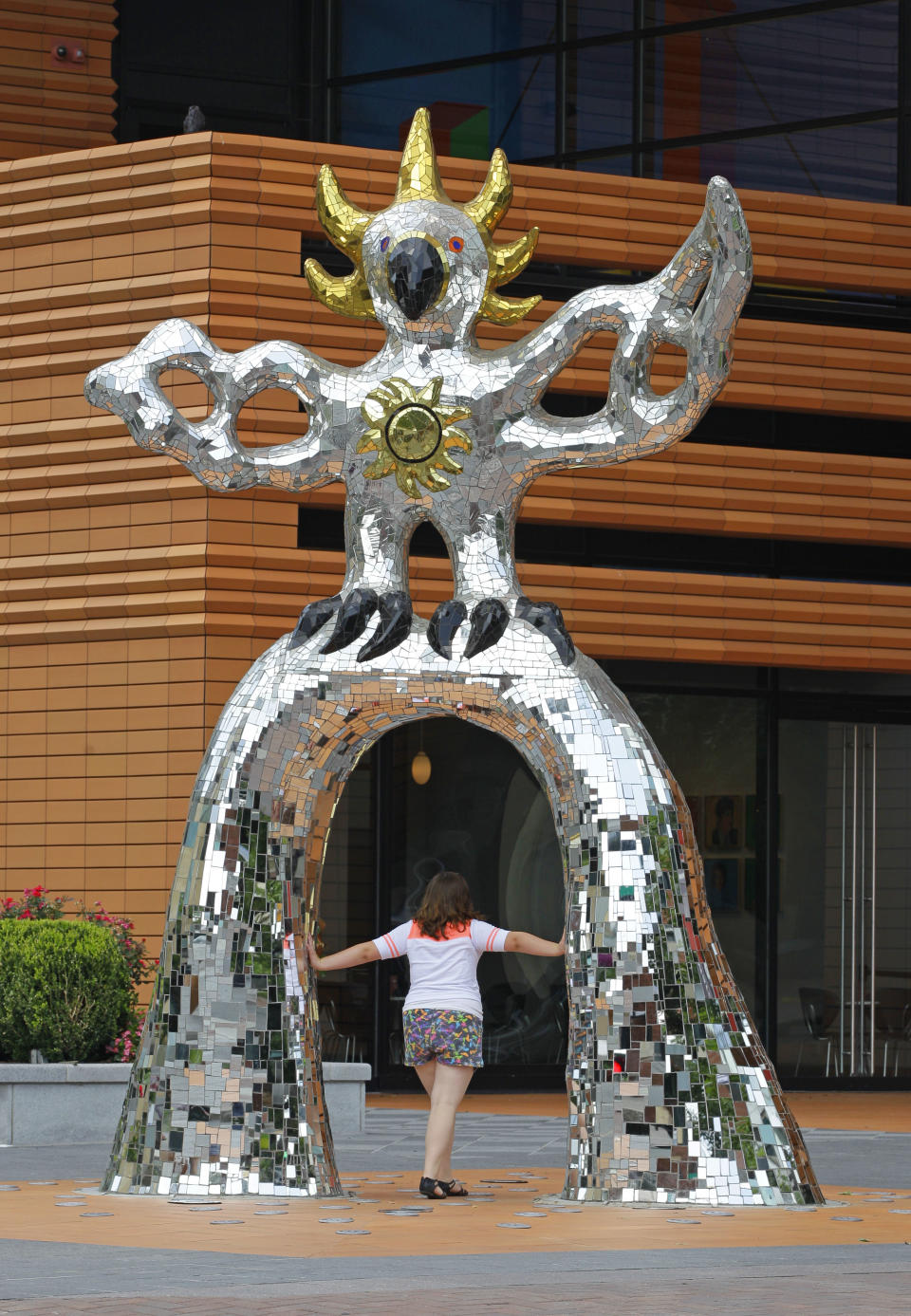 This July 17, 2012 photo shows a woman walking through the "Firebird" sculpture in front of the Bechtler Museum of Art in downtown Charlotte, N.C. (AP Photo/Chuck Burton)