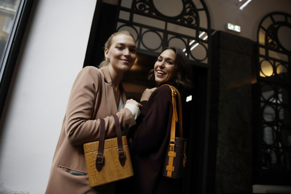 Model Arizona Muse, left, is flanked by designer Allison Hoeltzel Savini as they present a creation of the Officina del Poggio women's Fall-Winter 2019-2020 collection, in Milan, Italy, Sunday, Feb.24, 2019. (AP Photo/Luca Bruno)