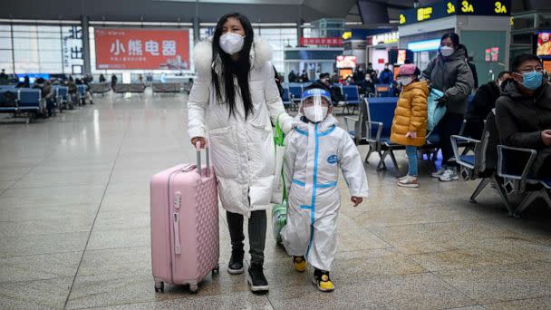 PHOTO: A woman leading child with personal protective equipment walks at a railway station in Beijing on Jan. 12, 2023, as the annual migration begins with people heading back to their hometowns for Lunar New Year celebrations. (Wang Zhao/AFP via Getty Images)