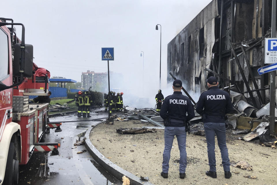 Italian police stand by as firefighters work at the site of a plane crash, in San Donato Milanese suburb of Milan, Italy, Sunday, Oct. 3, 2021. According to media reports, a small plane carrying five passengers and the pilot crashed into an apparently vacant office building in a Milan suburb. Their fates were not immediately known. (Italian Police via AP)