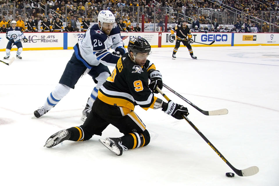 Pittsburgh Penguins' Evan Rodrigues (9) gets off a backhand pass with Winnipeg Jets' Blake Wheeler (26) defending during the second period of an NHL hockey game in Pittsburgh, Sunday, Jan. 23, 2022. (AP Photo/Gene J. Puskar)