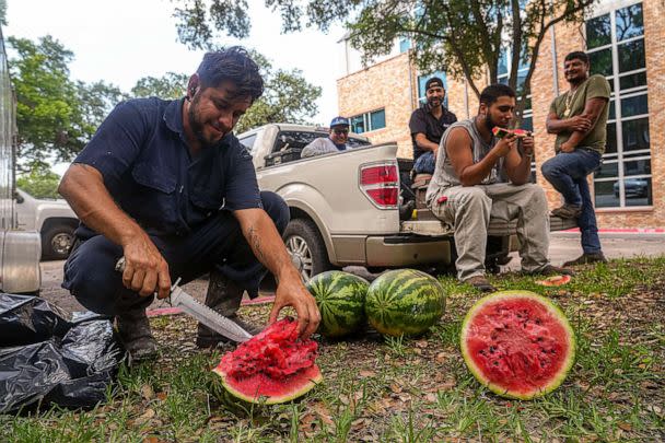 PHOTO: Junior Chavez, a painter for Dart Construction, slices watermelon for his coworkers while taking a break from painting window frames on the Scottish Rite Dormitory, June 19, 2023, in Austin, Texas. (American-Statesman/USA Today Network)