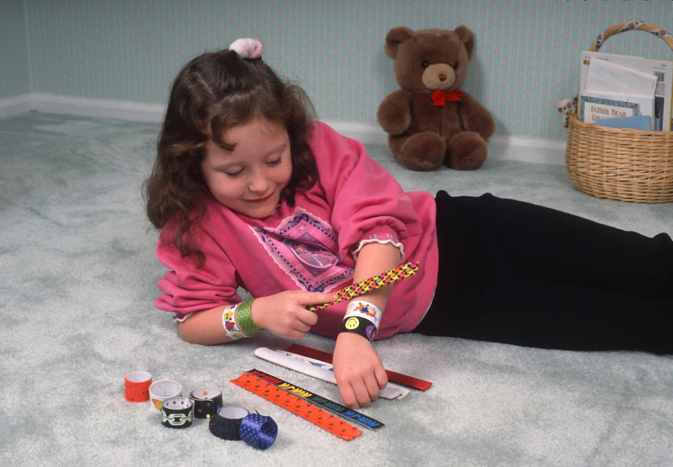 a girl putting on slap braclets