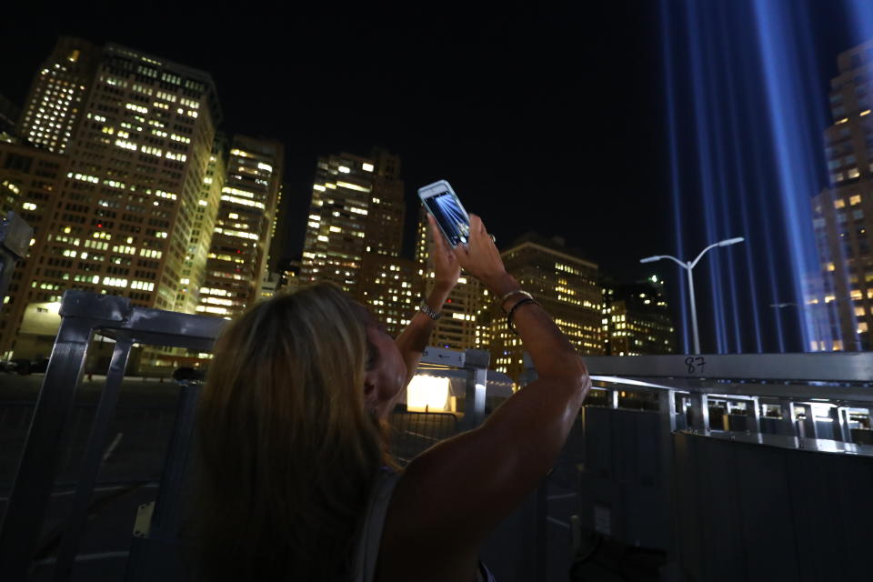 <p>A woman takes a photo of the Tribute in Light with her mobile device from a rooftop on Sept. 5, 2018. (Photo: Gordon Donovan/Yahoo News) </p>