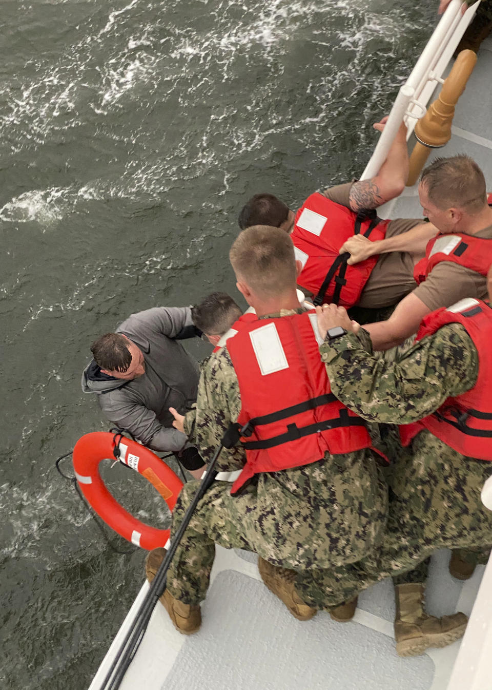 In this photo provided by the U.S. Coast Guard, crew members of the Coast Guard Cutter Glenn Harris pull a person from the water Tuesday, April 13, 2021 after a 175-foot commercial lift boat capsized 8 miles south of Grand Isle, La. The Seacor Power, an oil industry vessel, flipped over Tuesday in a microburst of dangerous wind and high seas. (U.S. Coast Guard via AP)