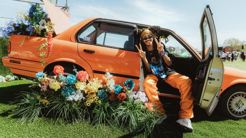 A Dreamville Festival-goer poses in the passenger seat of a replica of the BMW E30 M3 that appears on the cover of Frank Ocean’s ‘Nostalgia, Ultra.’ - Credit: Julian Bajsel