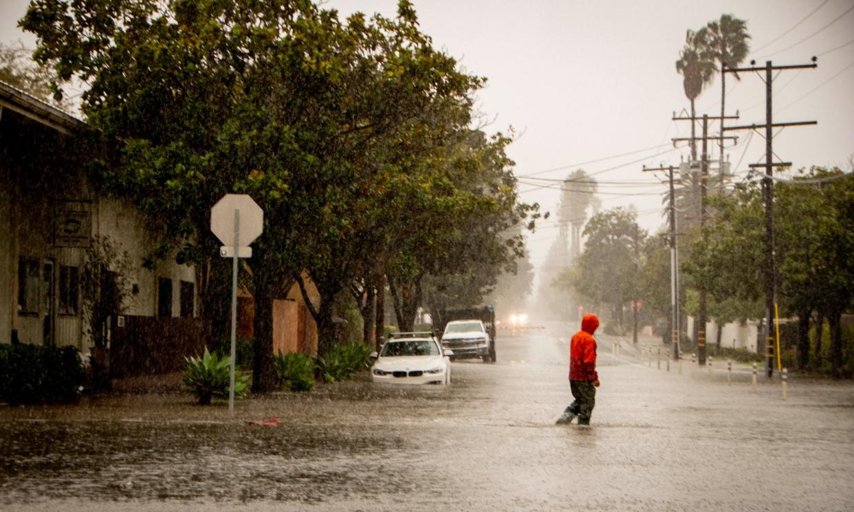 <span>A man crosses a flooded street during an atmospheric river in Santa Barbara, California, on 4 February 2024.</span><span>Photograph: Erick Madrid/EPA</span>