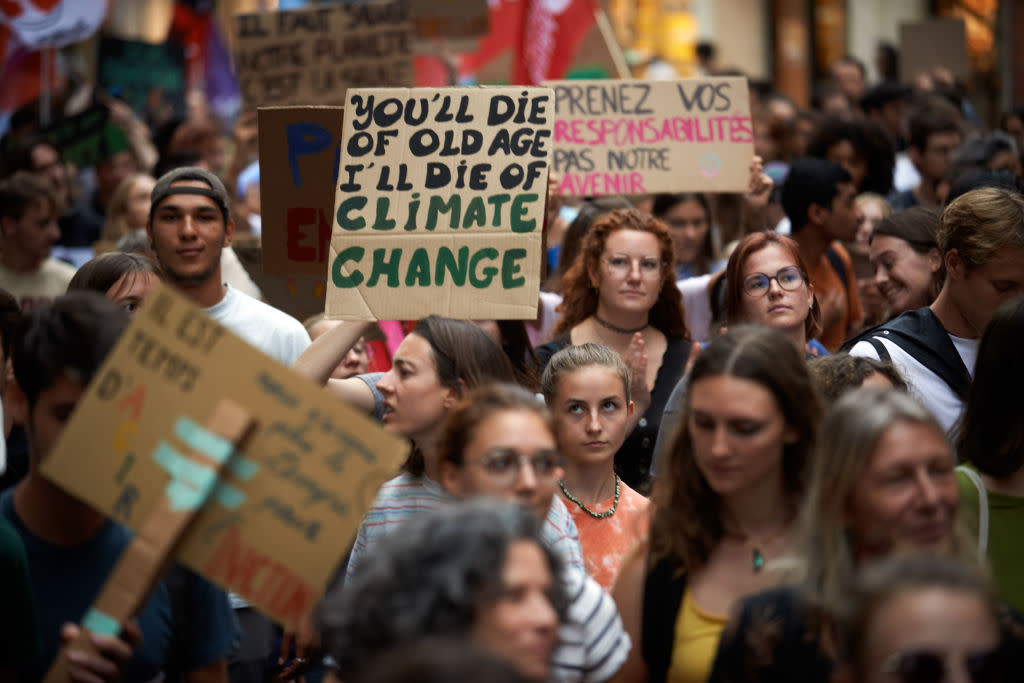During a climate protest, a protester holds a placard reading 'You'll die of old age, I will die of climate change'.