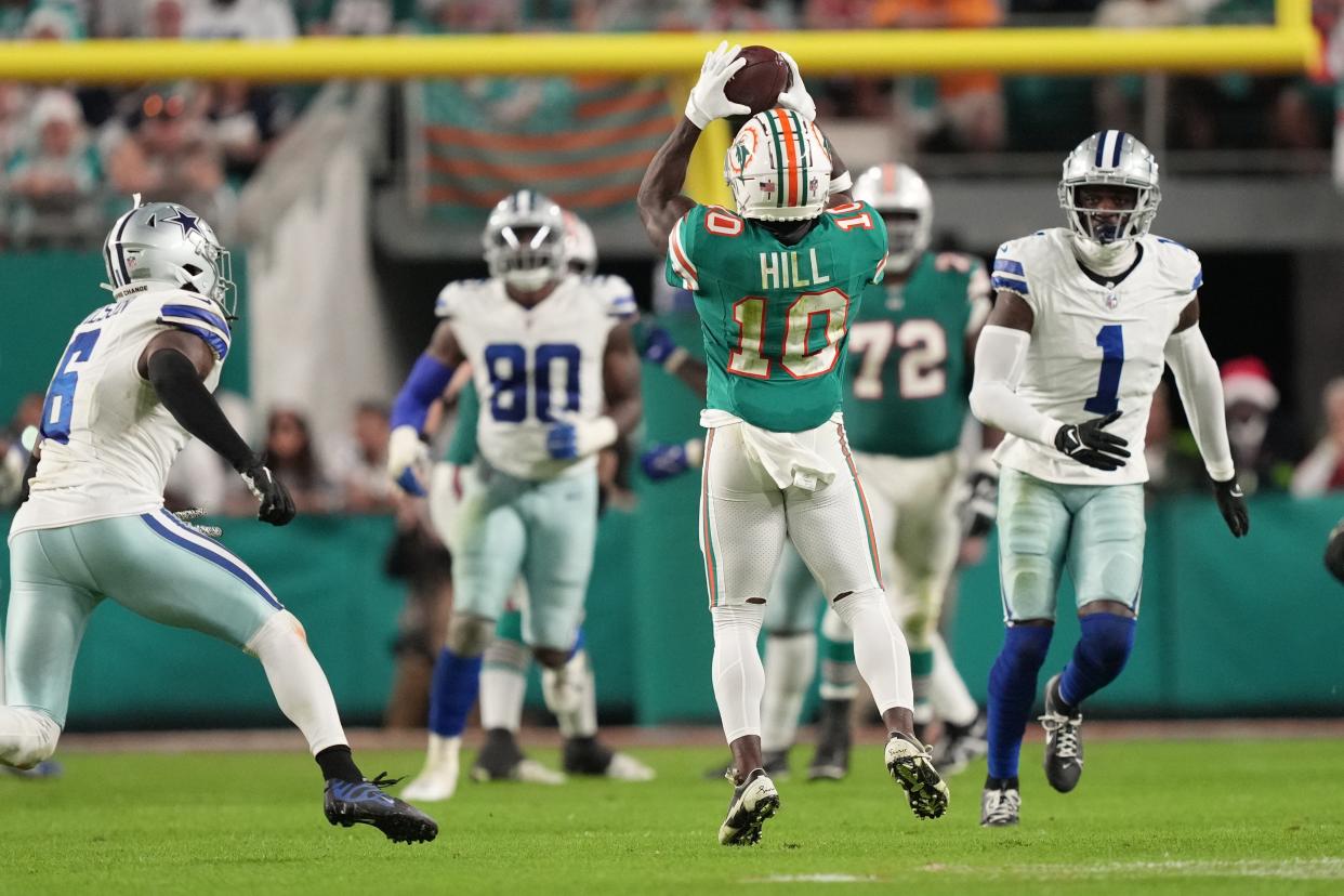 Miami Dolphins wide receiver Tyreek Hill (10) catches a pass in the middle of Dallas Cowboys defenders during the second half of an NFL game at Hard Rock Stadium in Miami Gardens, Dec. 24, 2023.