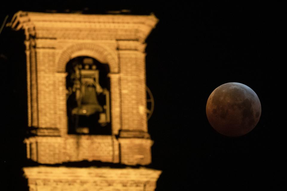 The so-called Super Blood Wolf Moon is pictured into Earth's dark umbral shadow during a total lunar eclipse over the 'San Bernardino's Church' in Saluzzo, Northwestern Italy on January 21, 2019. - An unusual set of celestial circumstances comes together on january 20 for skywatchers in Europe, Africa and the Americas, where a total lunar eclipse may be glimpsed, offering a view of a large, red Moon. (Photo by MARCO BERTORELLO / AFP) (Photo credit should read MARCO BERTORELLO/AFP/Getty Images)