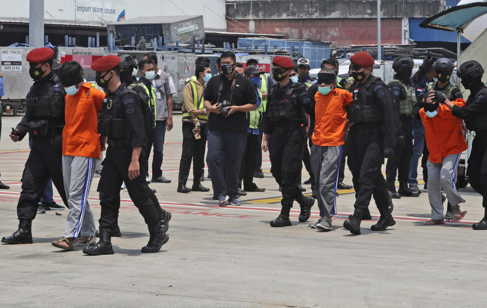 Police escort suspected militants upon arrival at the Soekarno-Hatta International Airport in Tangerang, Indonesia, Thursday, March 18, 2021. Indonesian authorities on Thursday transferred suspected militants arrested in raids in the last few weeks, from East Java to the capital city for further questioning. The militants are believed to be connected to linked to the al-Qaida-linked Jemaah Islamiyah extremist group. (AP Photo/Achmad Ibrahim)