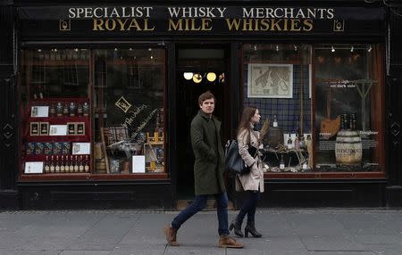 Pedestrians walk past a whisky shop on the Royal Mile, a busy street which runs from Edinburgh Castle to Holyrood Palace, in Edinburgh, Scotland, May 1, 2014. REUTERS/Suzanne Plunkett