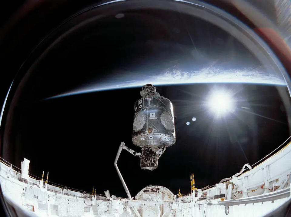 Foto aufgenommen an Bord der ISS während der Erstmontage.  Ein Modul steht aufrecht in der Mitte, mit der Erde dahinter.