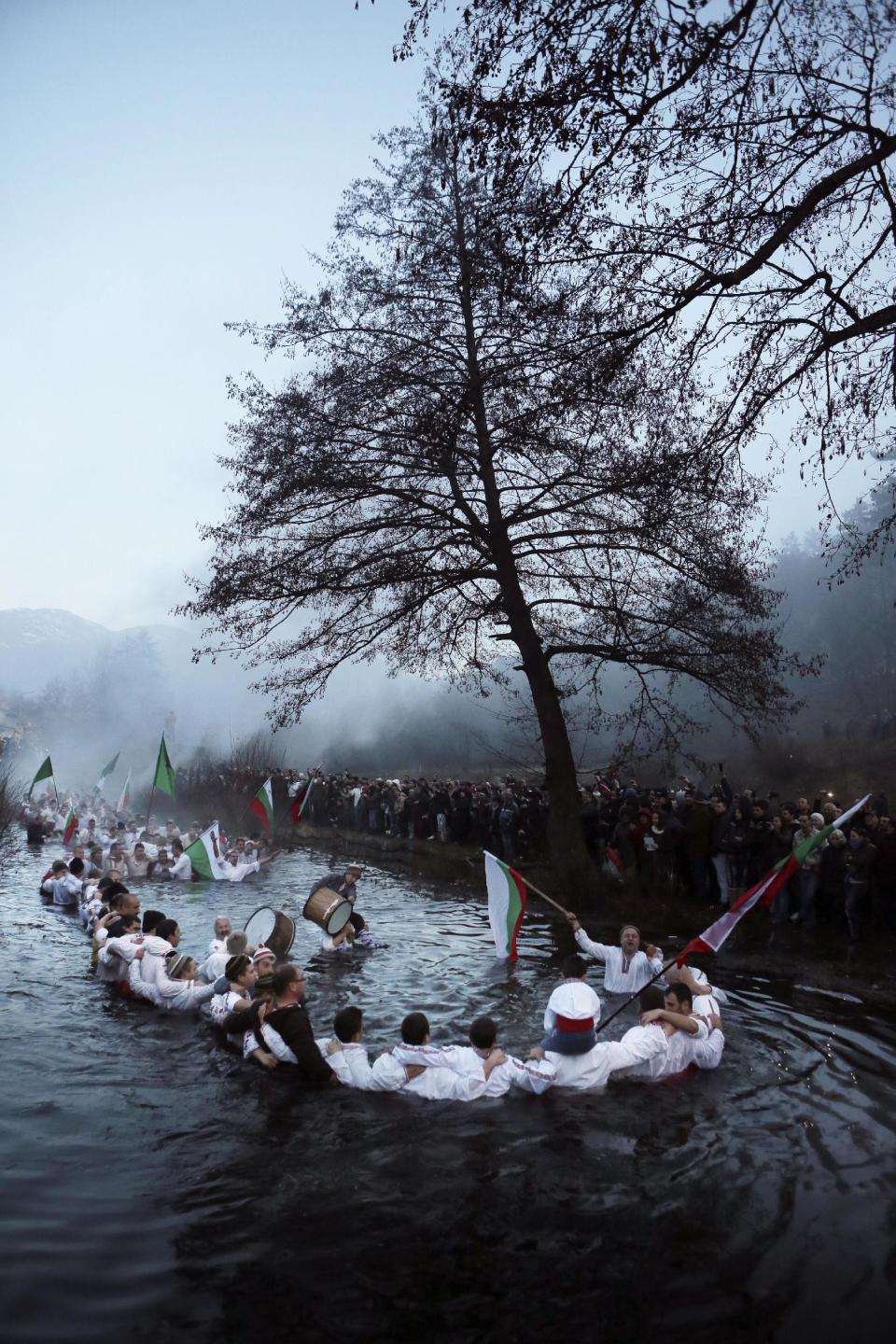 Believers sing and dance in the river Tundzha as they celebrate Epiphany day in the town of Kalofer, Bulgaria, Monday, Jan. 6, 2014. Traditionally, an Eastern Orthodox priest throws a cross in the river and it is believed that the one who retrieves it will be healthy through the year. (AP Photo/Valentina Petrova)