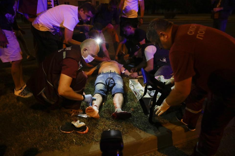 Paramedics treat a wounded person after clashes with police man in Minsk, Belarus, Sunday, Aug. 9, 2020. Police and protesters clashed in Belarus' capital and the major city of Brest on Sunday after the presidential election in which the authoritarian leader who has ruled for a quarter-century sought a sixth term in office. (AP Photo/Sergei Grits)