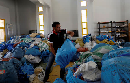 A Palestinian worker carries a bag containing items sent by mail eight years ago, after Israel allowed the letters and goods into the West Bank from Jordan, where they were being held, Jericho, in the occupied West Bank August 19, 2018. REUTERS/Mohamad Torokman