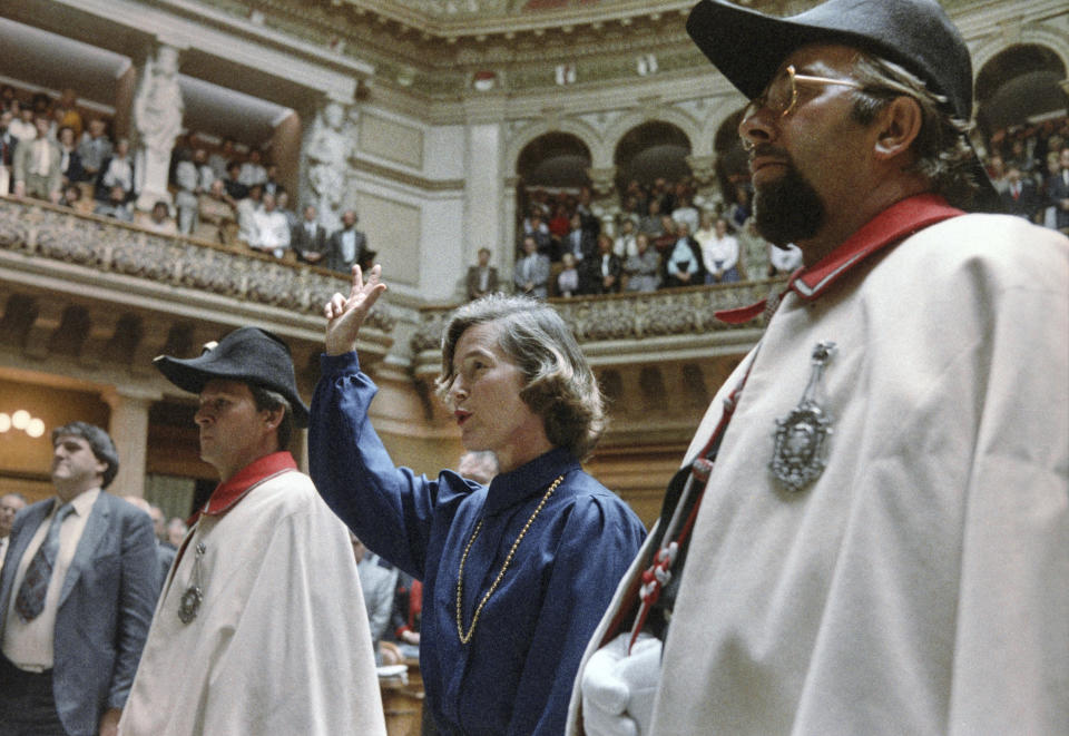 Elisabeth Kopp, raises her right hand to take the oath in the National Council Chamber in Bern, on Oct. 2, 1984. Elisabeth Kopp, a former prominent Swiss figure skater who became the first woman elected to Switzerland's seven-member executive branch and rose to vice president, has died, the federal chancellery said Friday April 14, 2023. She was 86. (Keystone via AP)