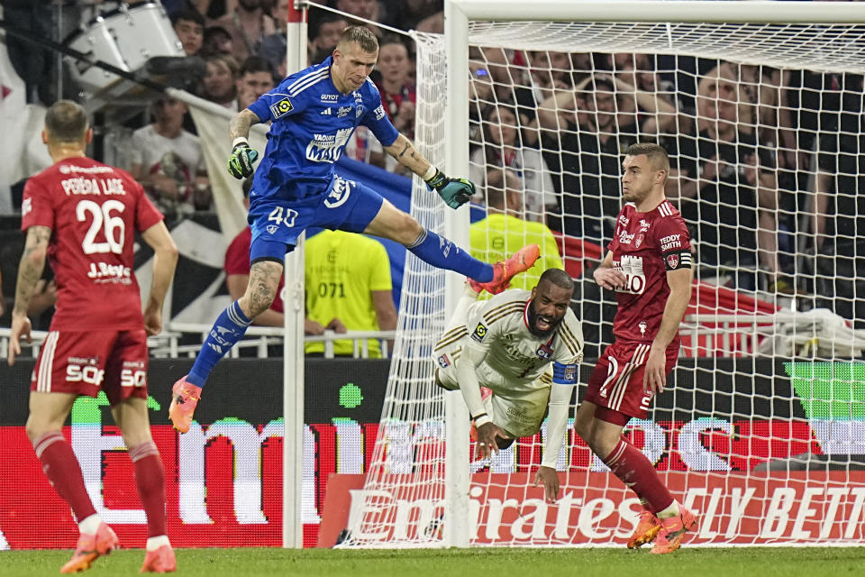 Lyon's Alexandre Lacazette, second from right, if fouled by Brest's goalkeeper Marco Bizot, top, during a French League One soccer match between Lyon and Brest at the Groupama stadium, outside Lyon, France, Sunday, April 14, 2024. (AP Photo/Laurent Cipriani)