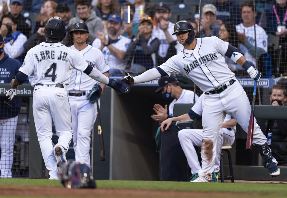 Seattle Mariners' Shed Long Jr. (4) is congratulated by Ty France (23) after scoring on a passed ball during the second inning of a baseball game against the Minnesota Twins on Tuesday, June 15, 2021, in Seattle. (AP Photo/Stephen Brashear)