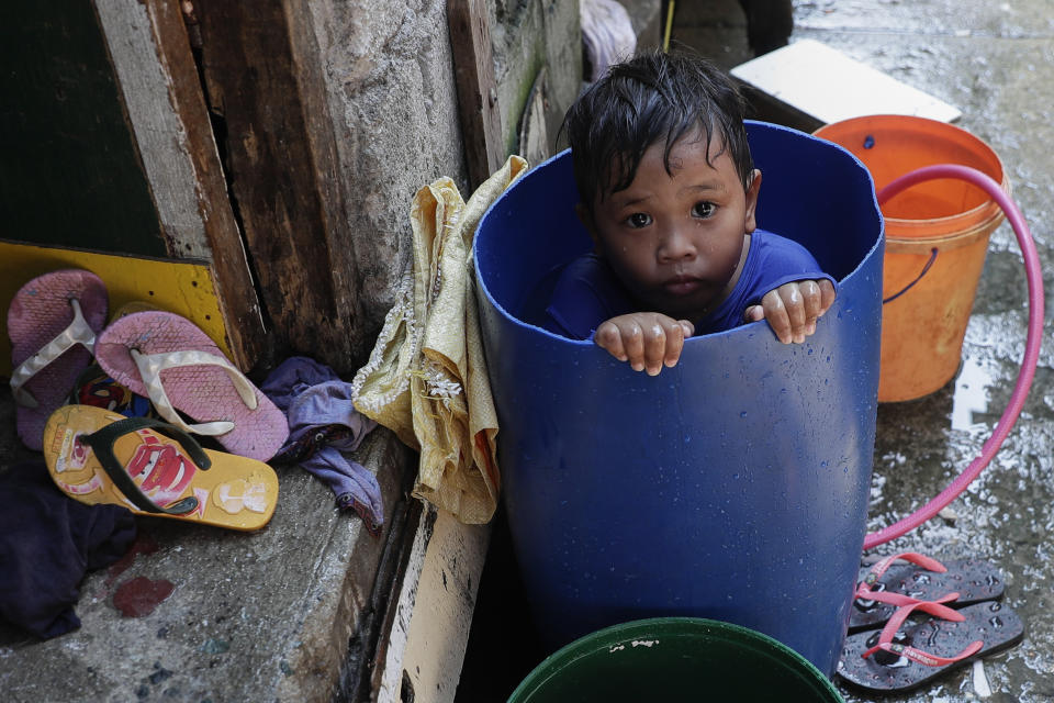 A boy takes a bath inside a plastic container at a coastal village in Cavite province, south of Manila, Philippines, during a continuing enhanced community quarantine to prevent the spread of the new coronavirus, Thursday, May 7, 2020. (AP Photo/Aaron Favila)