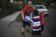 Michael Grunke help his neighbor's children with a case of water during his neighborhood watch activity, which started after the police custody death of George Floyd sparked unrest, Tuesday June 2, 2020, in Minneapolis, Minn. A week of civil unrest has led some Minneapolis residents near the epicenter of the violence to take steps to protect their homes and neighborhoods. (AP Photo/Bebeto Matthews)