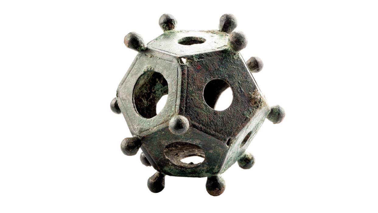  A photo of a metal, baseball-size Roman dodecahedron against a white background. 