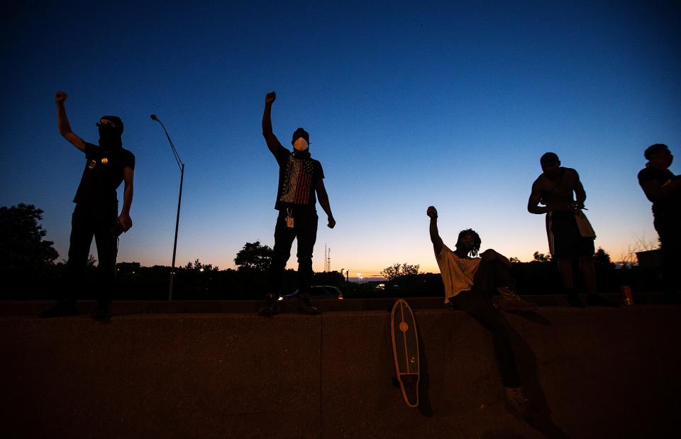 A group of men raise their fists after making their way on Interstate 75 Northbound and stopping traffic in Cincinnati on May 29, 2020.