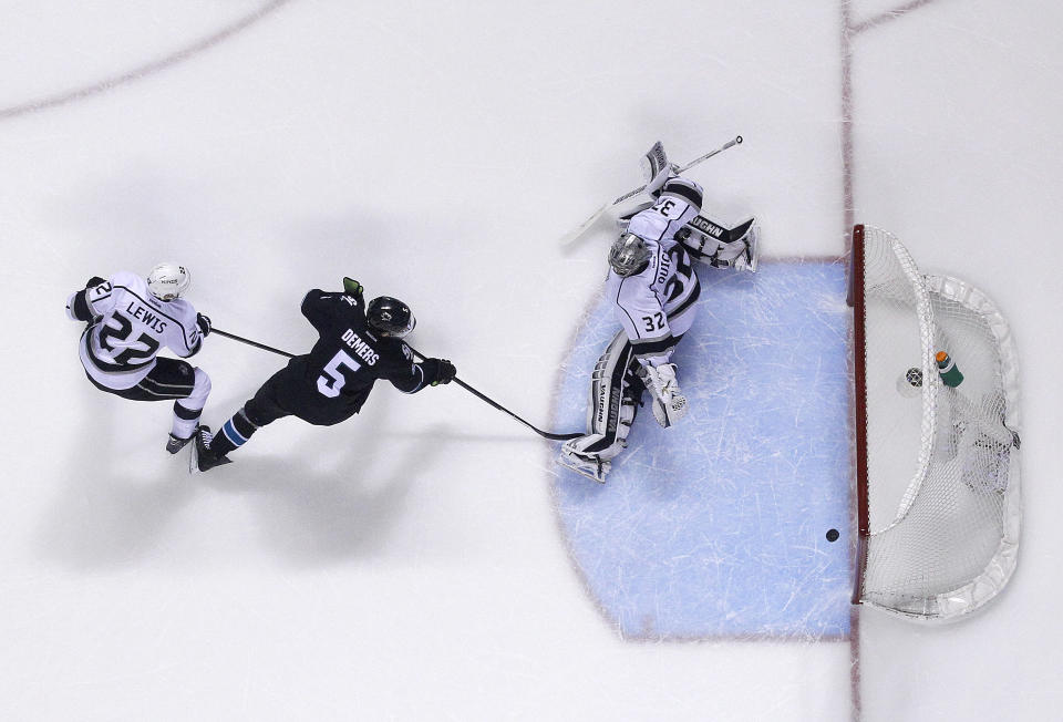 Los Angeles Kings goalie Jonathan Quick (32) blocks a goal attempt by San Jose Sharks defenseman Jason Demers (5) as Los Angeles Kings center Trevor Lewis (22) defends during the third period of Game 4 of an NHL hockey first-round playoff series in San Jose, Calif., Saturday, April 26, 2014. Los Angeles won 3-0. (AP Photo/Tony Avelar)