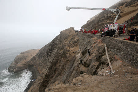 Rescue workers work at the scene after a bus crashed with a truck and careened off a cliff along a sharply curving highway north of Lima, Peru, January 3, 2018. REUTERS/Guadalupe Pardo