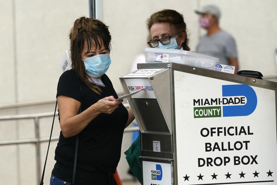 An election worker places a vote-by-mail ballot into an official ballot drop box outside of an early voting site, Monday, Oct. 19, 2020, in Miami. Florida begins in-person early voting in much of the state Monday. With its 29 electoral votes, Florida is crucial to both candidates in order to win the White House. (AP Photo/Lynne Sladky)