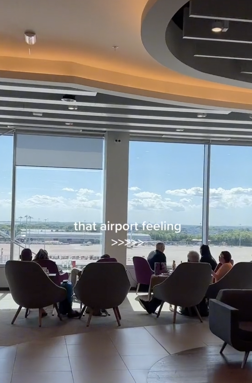 A screenshot of a TikTok, it shows people sitting in an airport looking out the windows, overlaid text reads 'that airport feeling'