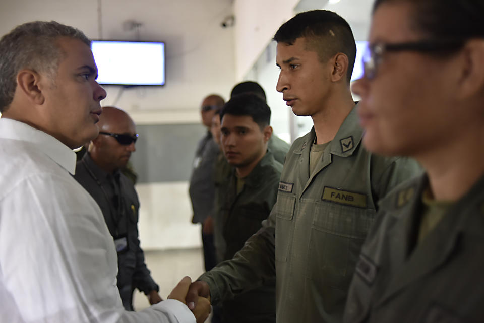 Colombia's President Ivan Duque, left, greets Venezuelan soldiers who defected as he visits the border area near Cucuta, Colombia, Sunday, Feb. 24, 2019. A U.S.-backed drive to deliver foreign aid to Venezuela on Saturday met strong resistance as troops loyal to Venezuelan President Nicolas Maduro blocked the convoys at the border and fired tear gas on protesters. (Nicolas Galeano/Colombian presidential press office via AP)