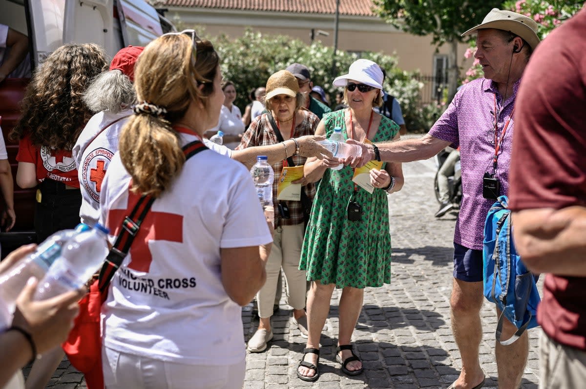 Red Cross volunteers hand out bottles of water in Athens (AFP via Getty Images)