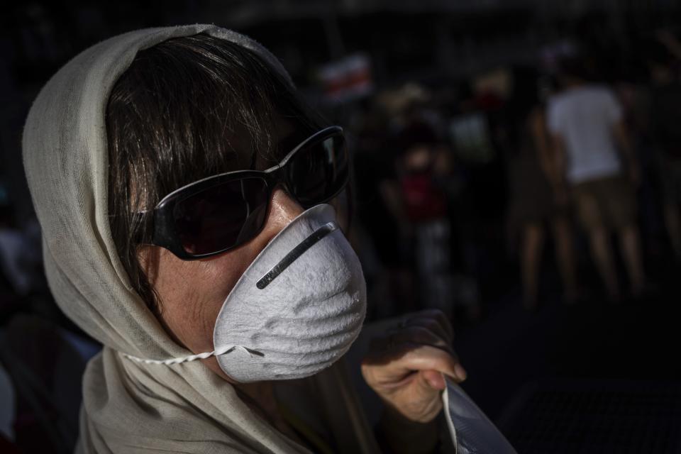 A citizen wears a mask during a rally in favor of a low-emission zone policy and against the new city council in Madrid, Spain, Saturday, June 29, 2019. The new municipality has decided to overturn ¨Madrid Central¨, an environment policy that banned most diesel and petrol cars within Madrid's downtown. The banner reads in Spanish ¨Less cars, better air¨. (AP Photo/Bernat Armangue)