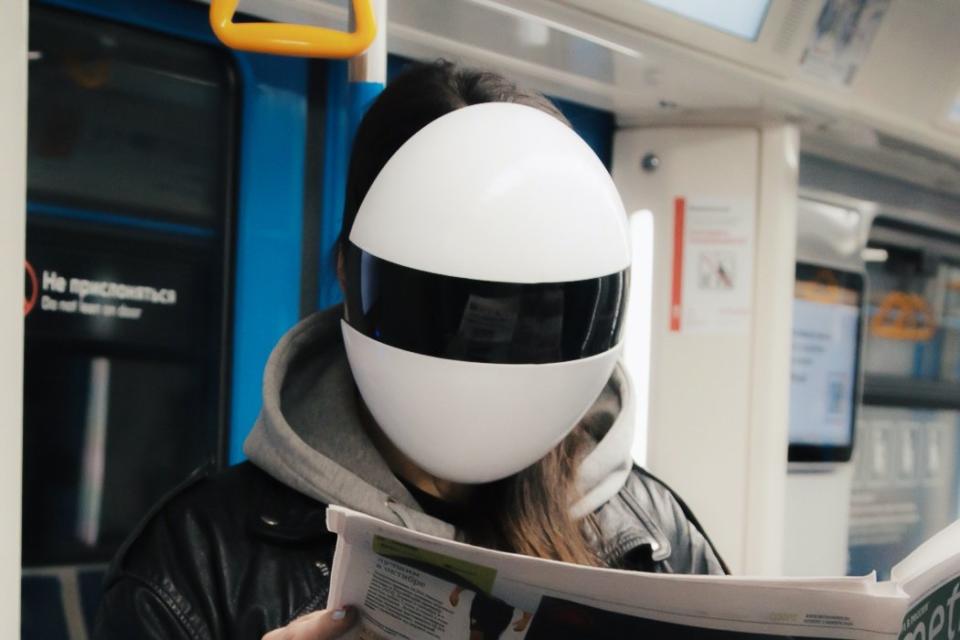 Woman wears her Blanc Full-Face Modular Mask while reading on the subway. 