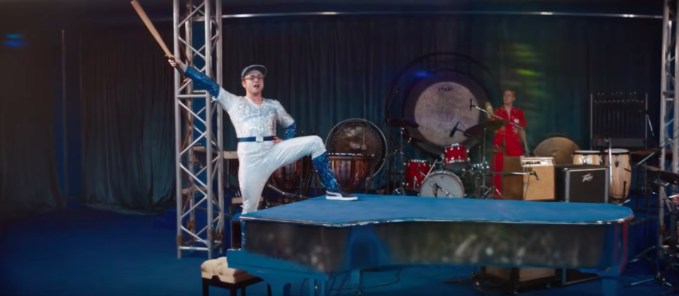 Elton John performing while wearing a jeweled baseball outfit in the film