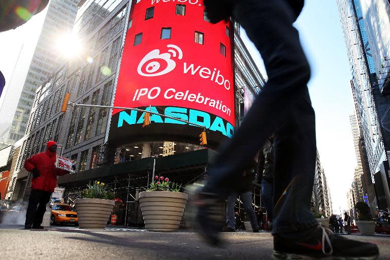 People walk by the Nasdaq exchange in Times Square moments before China's Weibo began trading on the Nasdaq exchange under the ticker symbol WB on April 17, 2014 in New York City